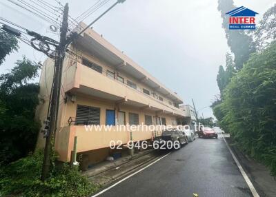 Exterior view of a residential building with a road and parked cars