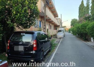 Apartment building exterior with parked cars and contact number