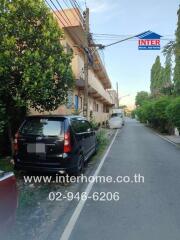 Apartment building exterior with parked cars and contact number