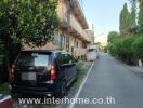 Apartment building exterior with parked cars and contact number