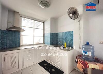 Kitchen with blue tiled backsplash and a water cooler.