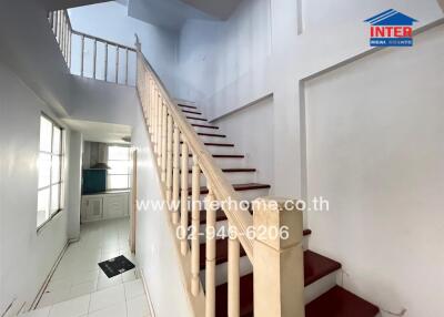 Bright staircase with white railing and red carpet steps in a house