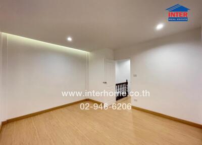 Empty bedroom with wooden floor and white walls.