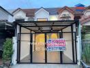 Front view of a house with a carport and a sign for sale by a real estate agency