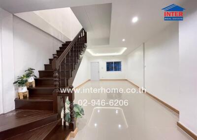 Interior view of a residential building with a staircase, bright ceiling lights, and glossy floor tiles