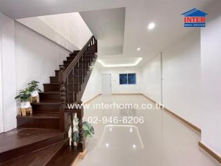 Interior view of a residential building with a staircase, bright ceiling lights, and glossy floor tiles