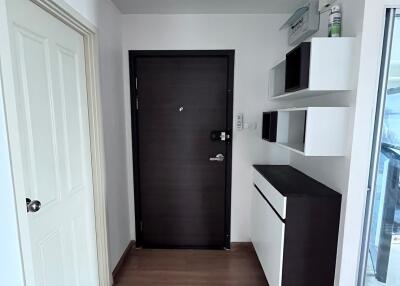 Modern entryway with dark wooden door, white wall shelves, and wooden floors