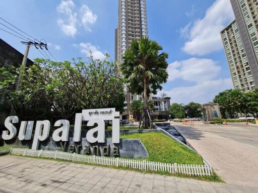 Exterior of high-rise apartment complex with landscaped entrance and signage