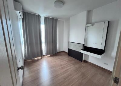 Empty bedroom with wooden floor, gray curtains, and wall-mounted mirror with shelf