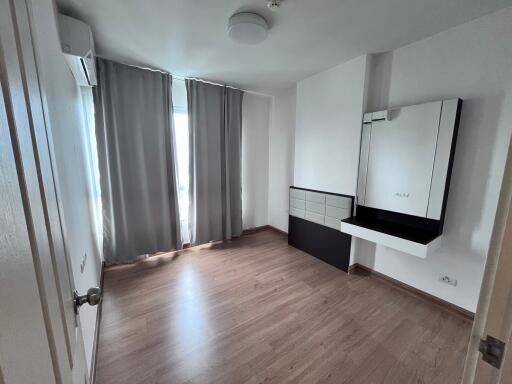 Empty bedroom with wooden floor, gray curtains, and wall-mounted mirror with shelf