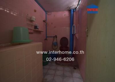 Dimly lit bathroom with pink tiled walls and various fixtures