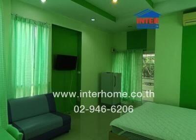 Bedroom with green decor including double bed, sofa, curtains, air conditioner, and television.