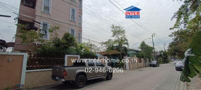 Street view of a residential area with houses and a pickup truck