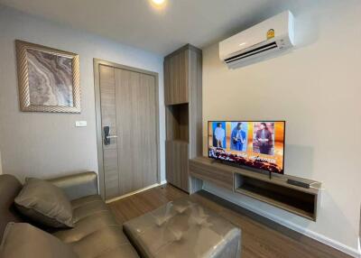 Modern living room with gray sofa, wall-mounted TV, and air conditioning unit