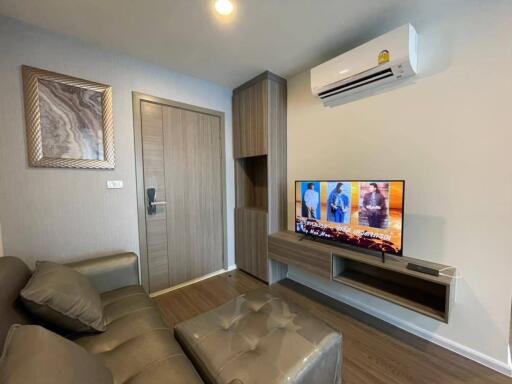 Modern living room with gray sofa, wall-mounted TV, and air conditioning unit