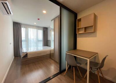 Bedroom with wooden flooring, bed with storage, large windows, small desk and chairs, and glass partition