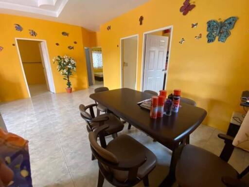 Bright dining room with yellow walls, butterfly decorations, and a dark wooden dining table with chairs