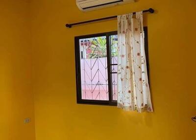 Bedroom with yellow walls, window with curtain, ceiling fan, and air conditioner