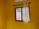 Bedroom with yellow walls, window with curtain, ceiling fan, and air conditioner