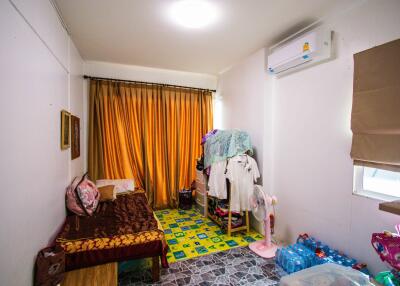 Small bedroom with single bed, various items, and air conditioning