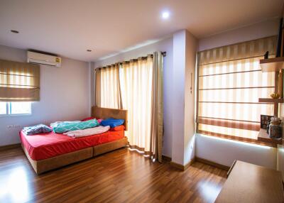 Well-lit bedroom with wooden flooring and large windows