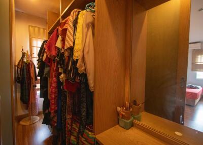 Walk-in closet with various clothes hanging and a vanity with a mirror