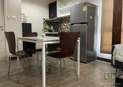 Modern kitchen and dining area with table and chairs, refrigerator, and tiled backsplash.