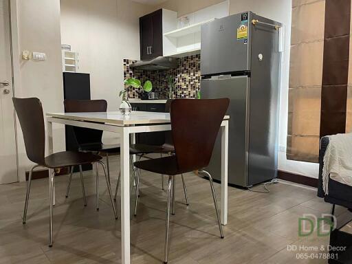 Modern kitchen and dining area with table and chairs, refrigerator, and tiled backsplash.