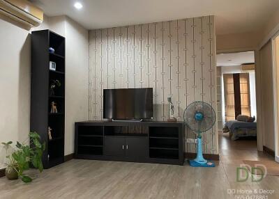 Living room with a TV stand, shelves, and a fan, showing an adjoining bedroom