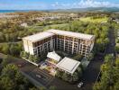 Aerial view of a modern residential building surrounded by greenery and scenic landscape