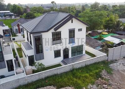 Aerial view of a modern two-story house with surrounding greenery and neighboring properties