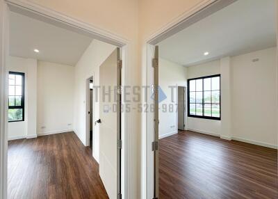 Two bedroom doors open to bright rooms with wooden floors