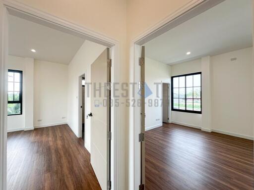 Two bedroom doors open to bright rooms with wooden floors