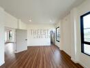 Empty living room with wooden floors and large windows