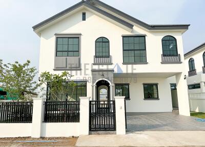 White two-story house with black window frames and gated front yard