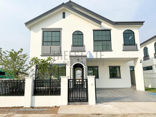 White two-story house with black window frames and gated front yard