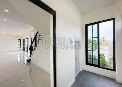 Modern interior view of a house with large windows, a staircase, and a spacious living area.