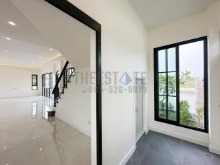 Modern interior view of a house with large windows, a staircase, and a spacious living area.