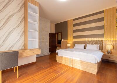 Spacious and modern bedroom with wooden floors, large bed, study desk, and ample natural light