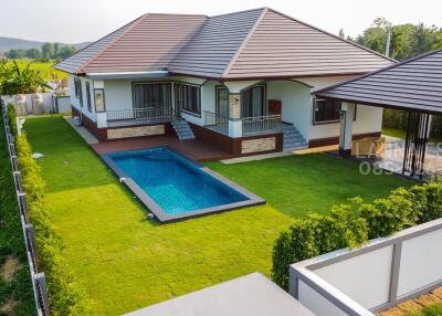 Aerial view of a modern house with a swimming pool and green lawn