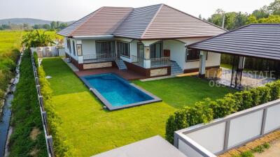 Aerial view of a modern house with a swimming pool and green lawn