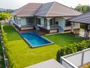 Aerial view of a modern house with a swimming pool and green lawn