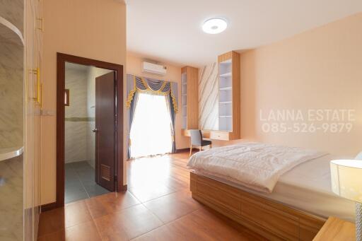 Spacious bedroom with natural light, en-suite bathroom, desk, and large bed