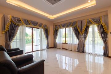 Spacious and well-lit living room with luxurious curtains and marble flooring