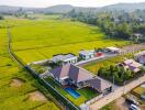 Aerial view of a residential house with a pool and surrounding green fields