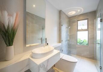 Modern bathroom with large mirror, elegant sink, shower area, and natural light