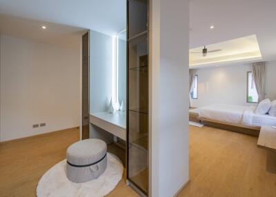 Modern bedroom with wooden flooring, a large bed, and a cozy seating area