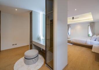 Modern bedroom with wooden flooring, a large bed, and a cozy seating area