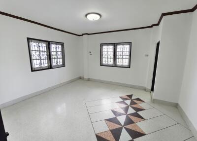 spacious white living room with decorative floor tiles and two windows