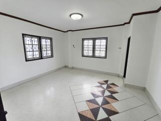 spacious white living room with decorative floor tiles and two windows